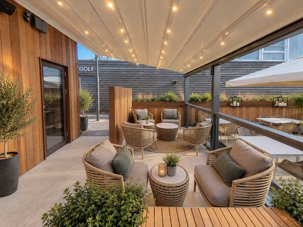 Lyst tag og glaspartier omkring en terrasse med beige loungestole.