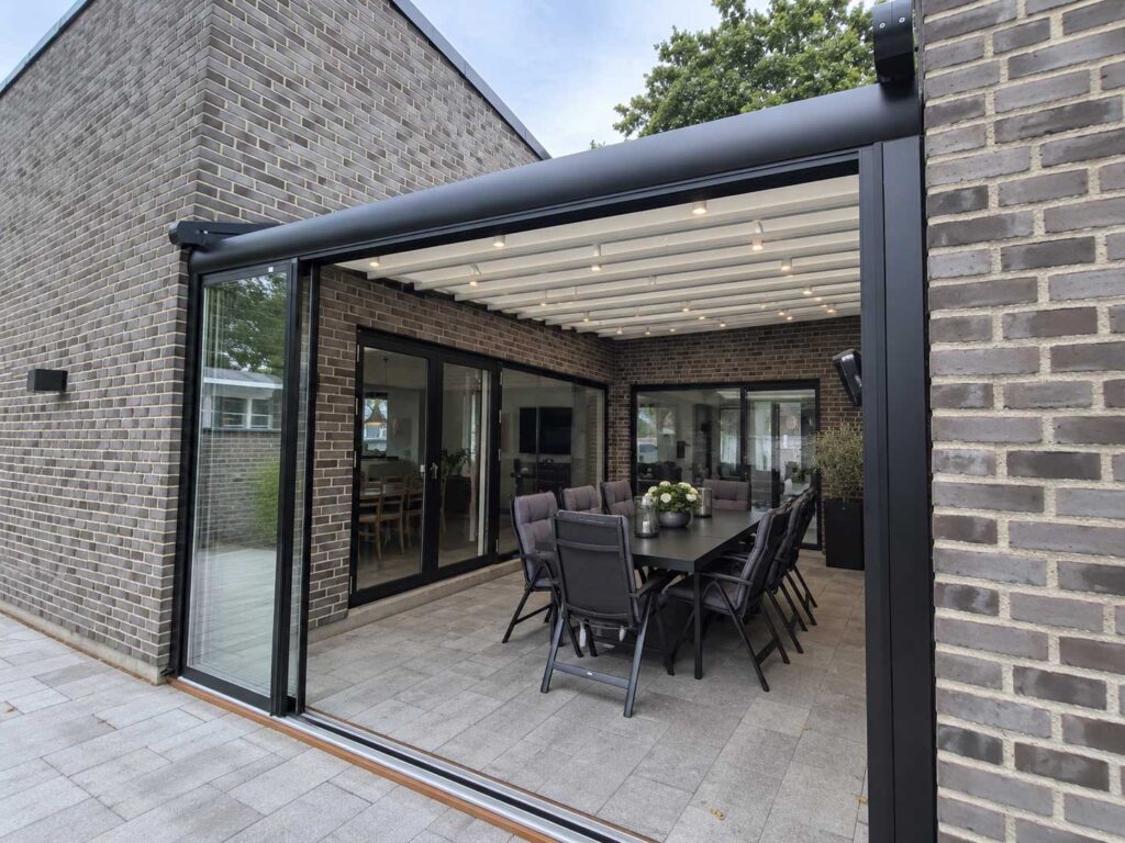 Mørk Ocean-pergola med delvist åbent tag over en terrasse ved et gråt murstenshus.