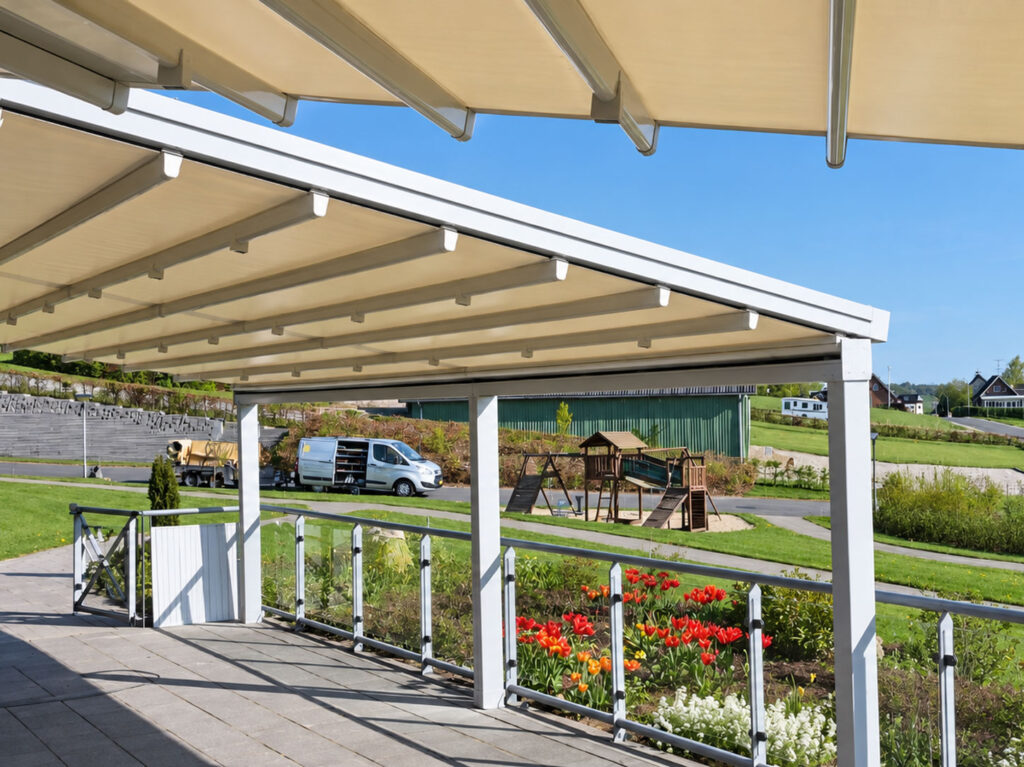 Lys terrasseoverdækning med hvide stolper, glaspartier og udsigt til haven.