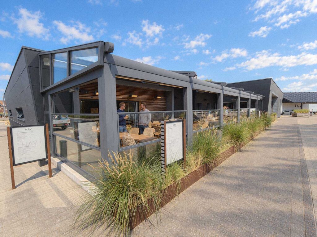 Mørk pergola med glasfront ved Henne Strand Resort, set fra et hjørne i dagslys.