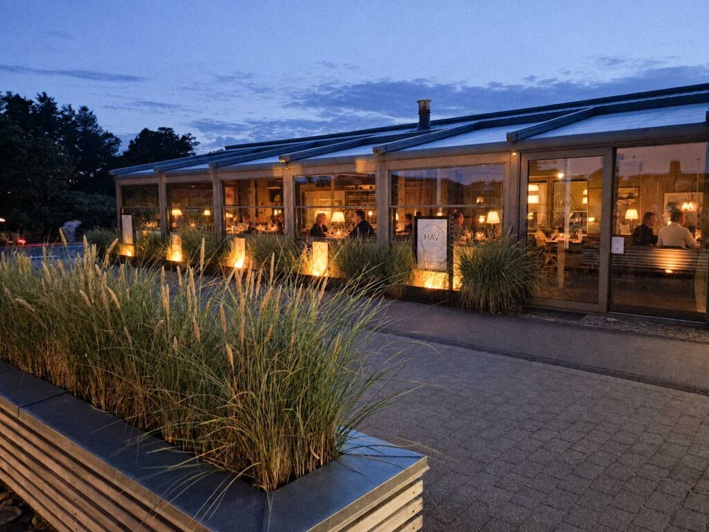 Lang terrasseoverdækning ved Henne Strand Resort med varm belysning om aftenen.