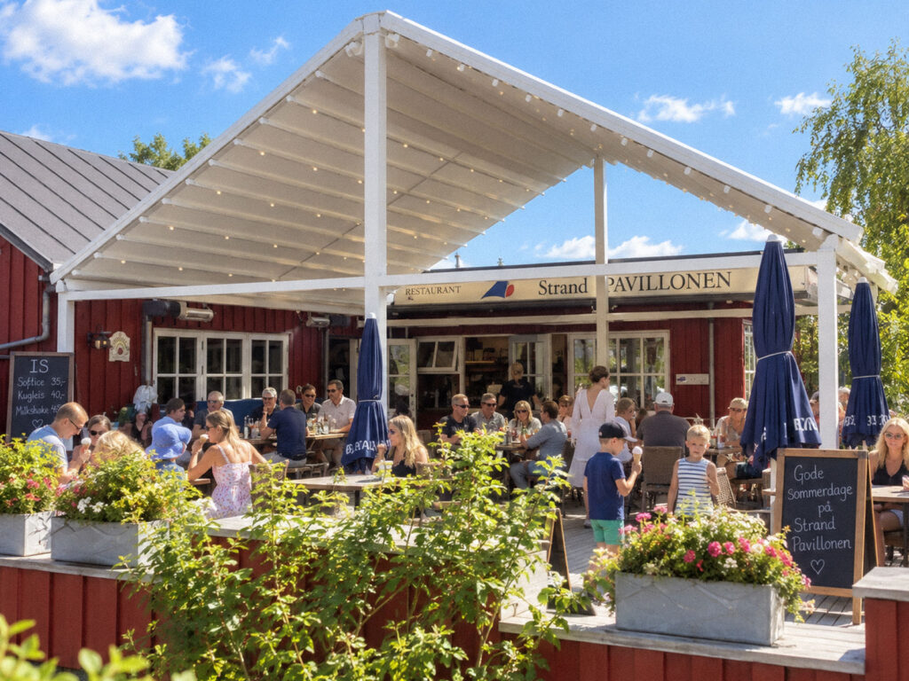 Stor, hvid pergola ved en rød restaurantbygning, set udefra.