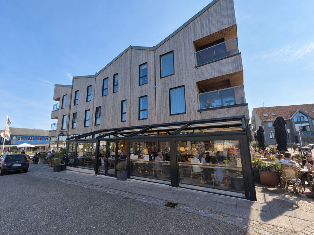Pergola og restaurantterrasse foran Restaurant Storm i en lys etagebygning.