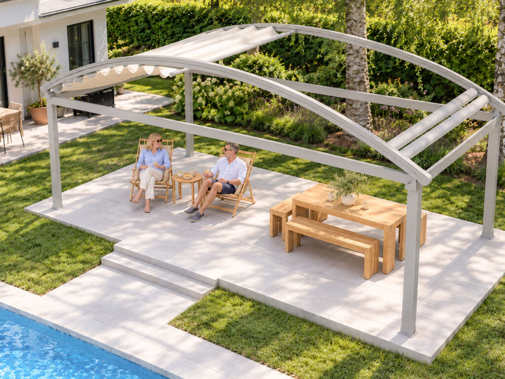 Luna-pergola set skråt ovenfra med buede tagspær, delvist tilbagetrukket dugtag og terrasse med liggestole og spisebord ved poolen.